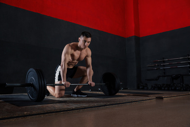 Strong man lifting barbell in modern gym