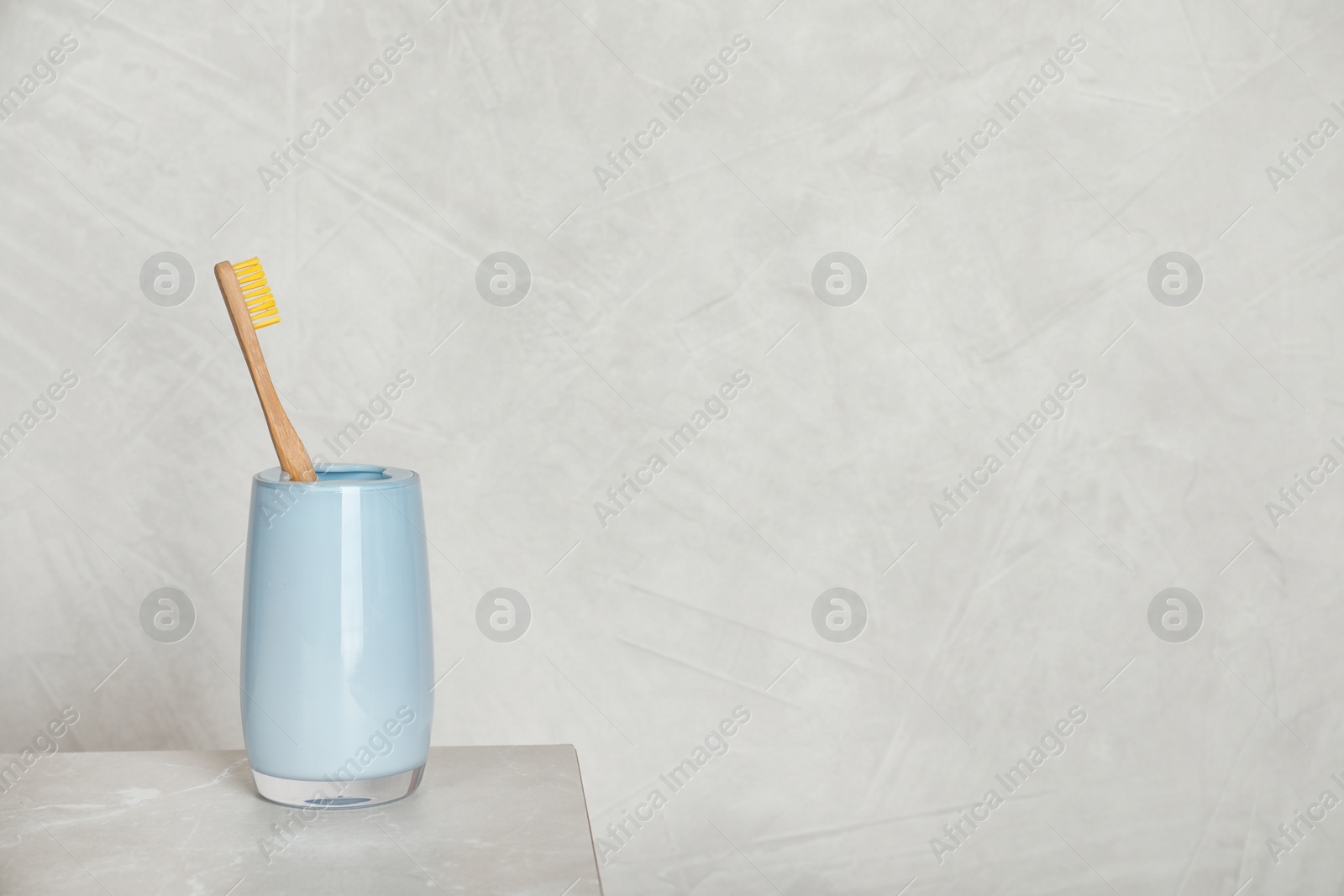 Photo of Holder with bamboo toothbrush on table against grey background. Space for text