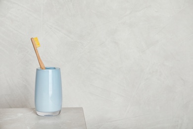 Photo of Holder with bamboo toothbrush on table against grey background. Space for text