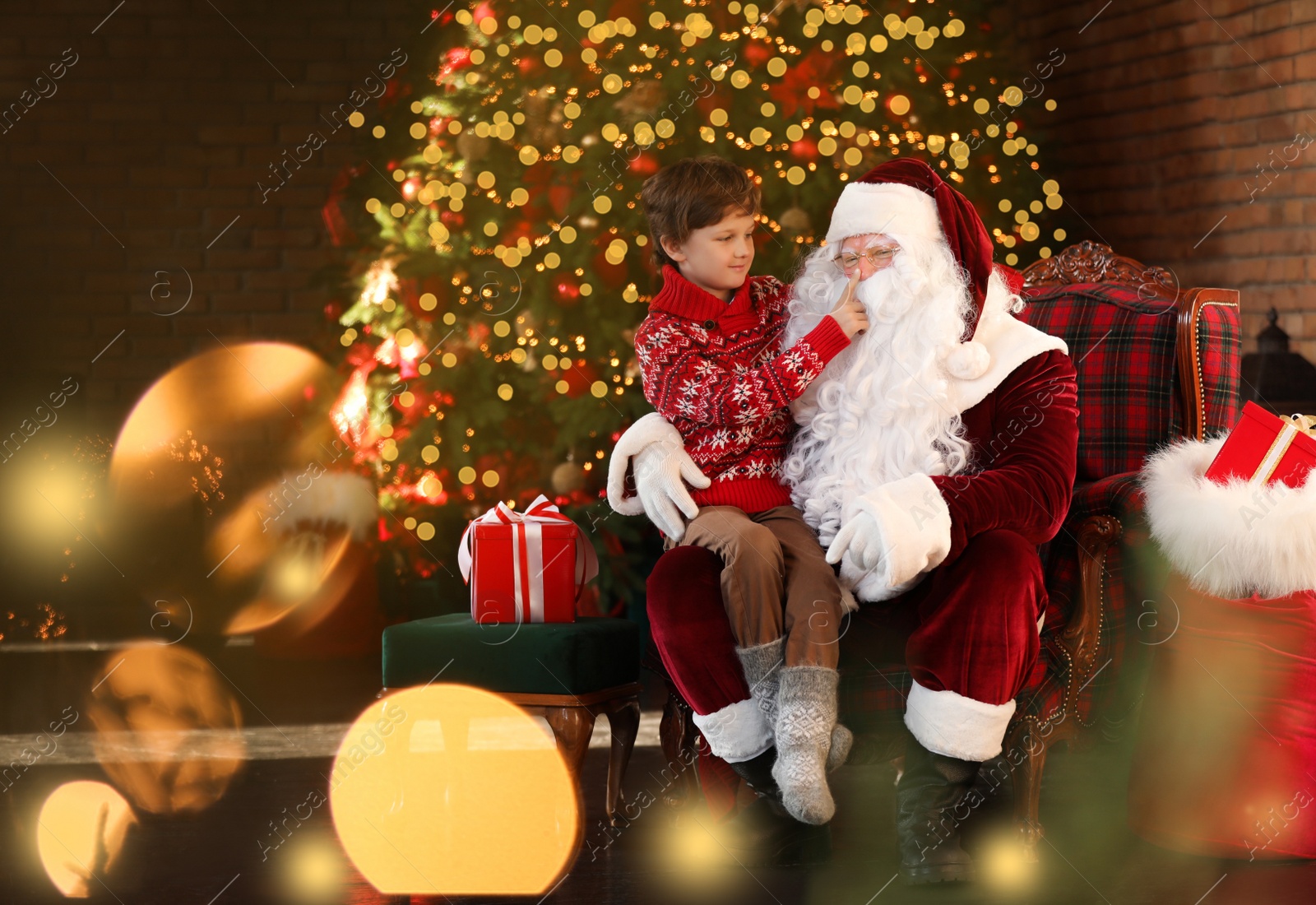 Photo of Santa Claus and little boy near Christmas tree indoors