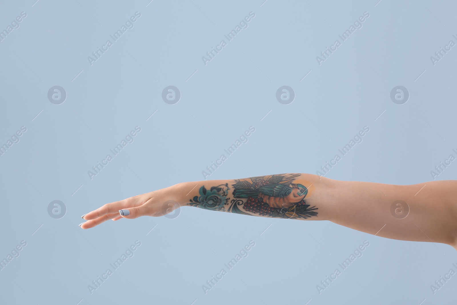 Photo of Female arm with tattoo on color background