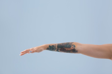 Female arm with tattoo on color background
