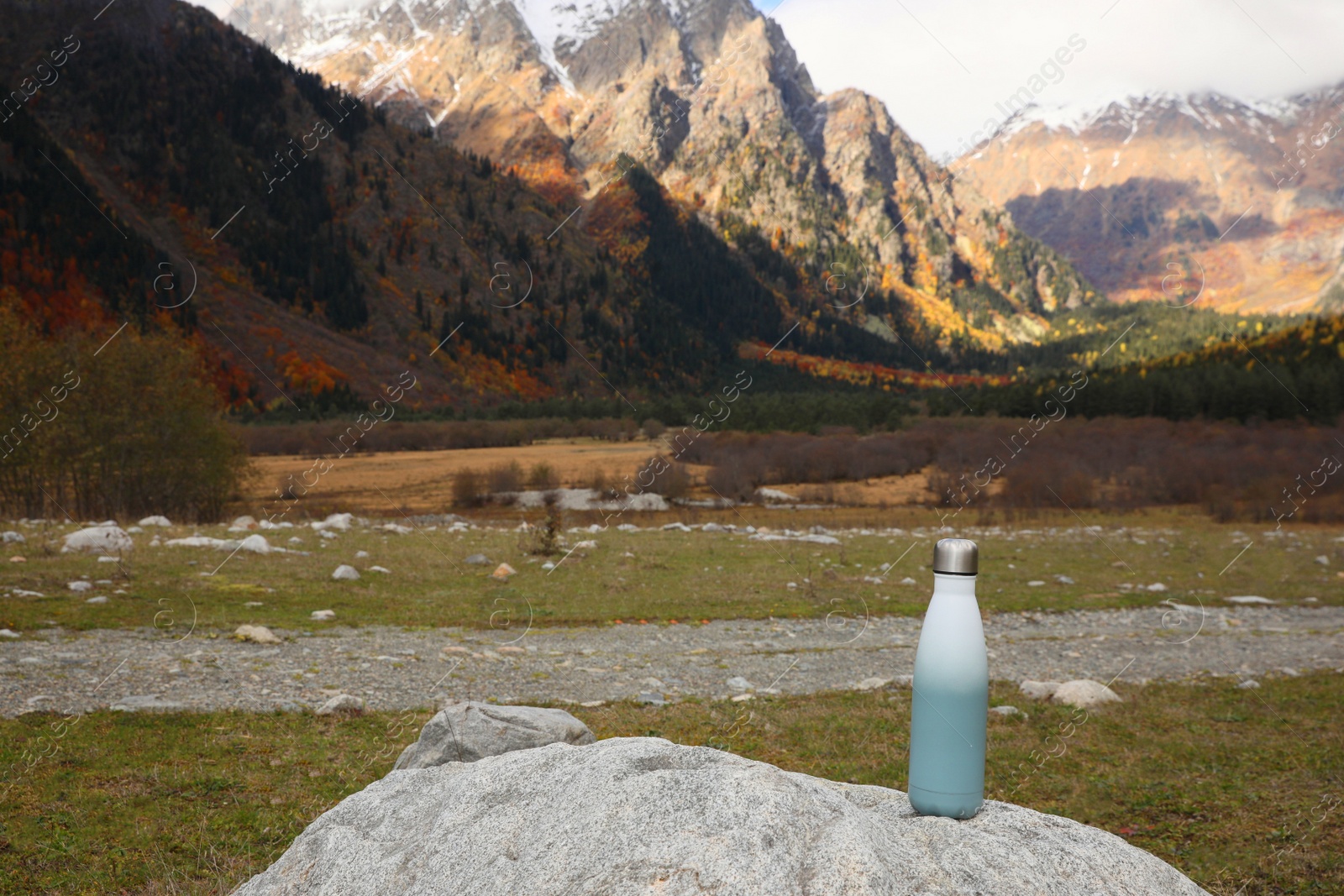 Photo of Thermo bottle on rock in mountains. Space for text