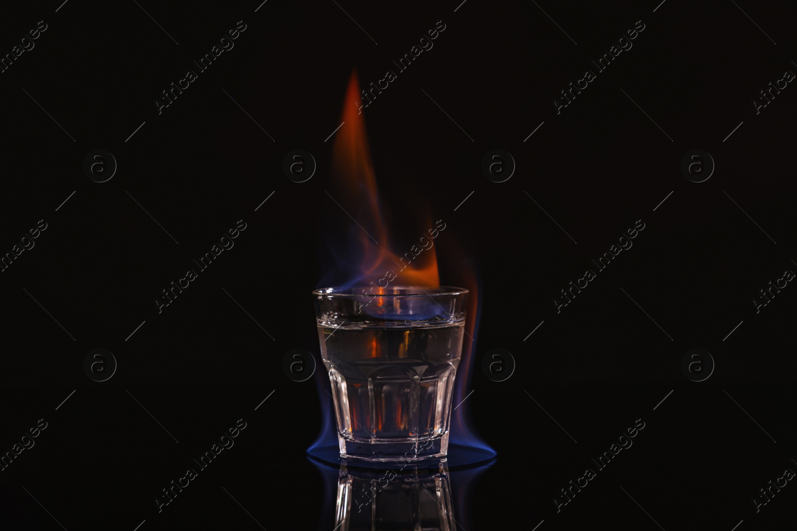 Photo of Flaming vodka in shot glass on black background