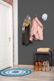 Photo of Modern hallway interior with stylish rug and clothes on wall