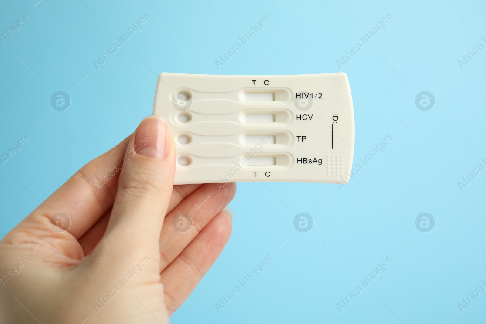 Photo of Woman holding disposable express test for hepatitis on light blue background, closeup