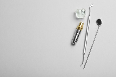 Parts of dental implant and tools on grey background, flat lay. Space for text