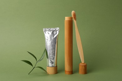 Photo of Bamboo toothbrush, paste and case on green background. Conscious consumption