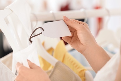 Photo of Young woman checking tag on clothes in boutique, closeup. Space for text