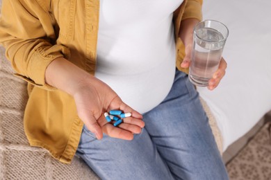 Photo of Pregnant woman taking pills on bed, closeup
