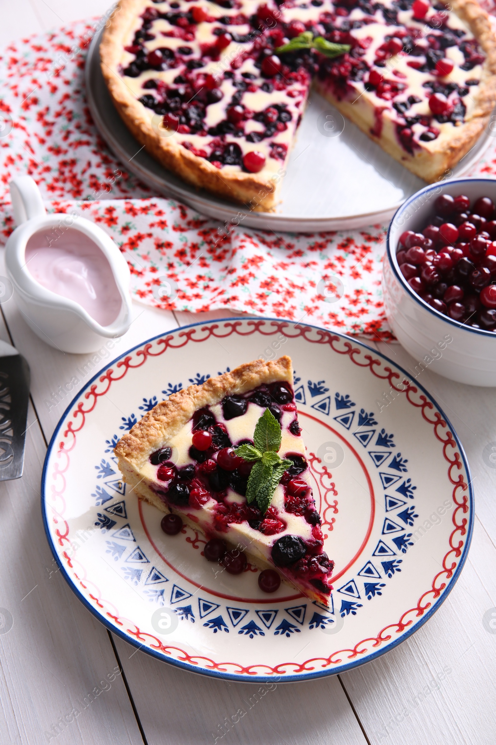 Photo of Piece of delicious currant pie served on white wooden table