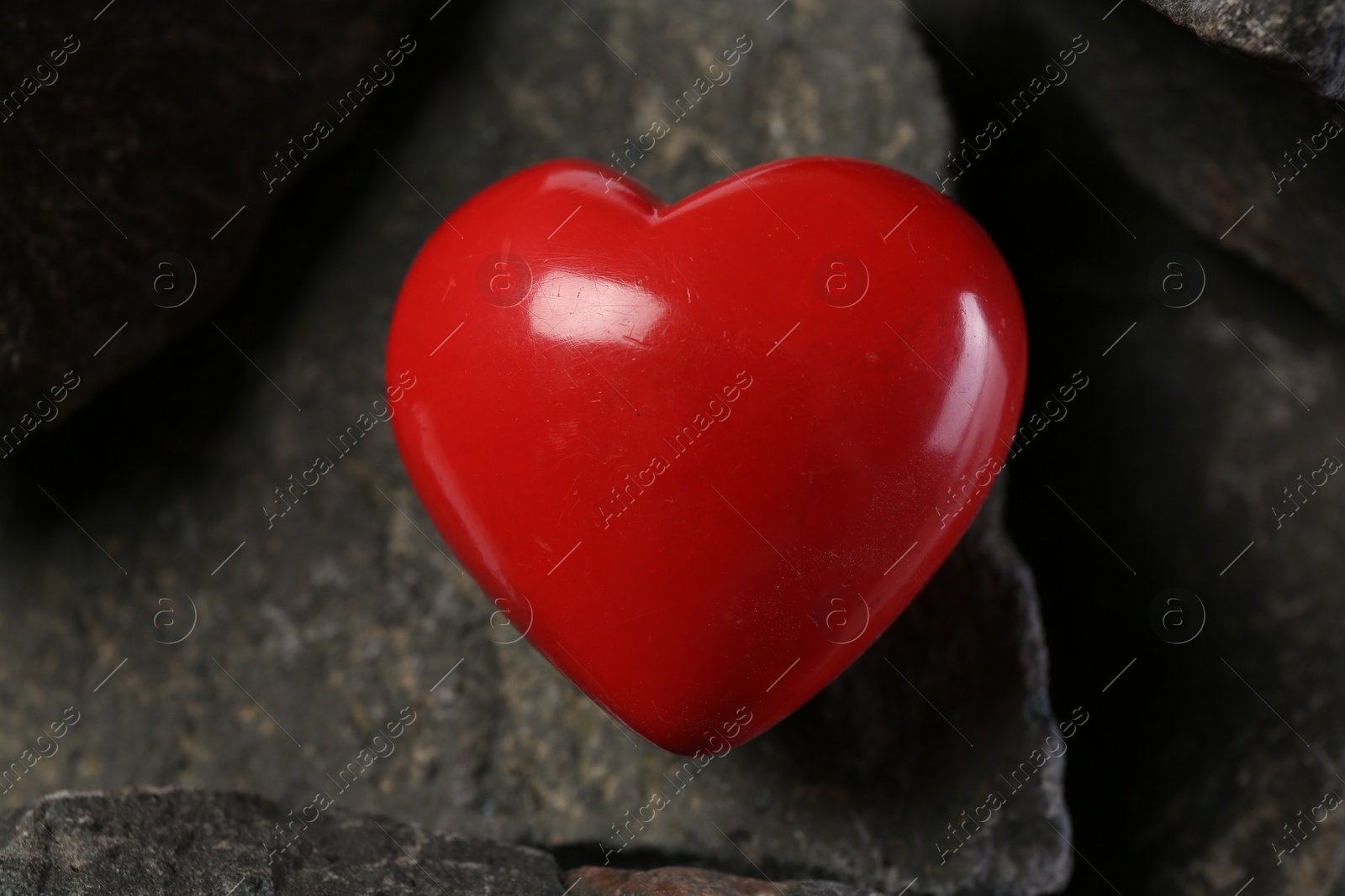 Photo of One red decorative heart on stones, closeup