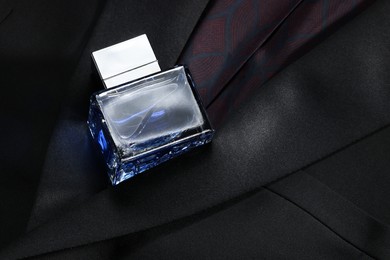 Photo of Luxury men's perfume in bottle on black jacket, space for text