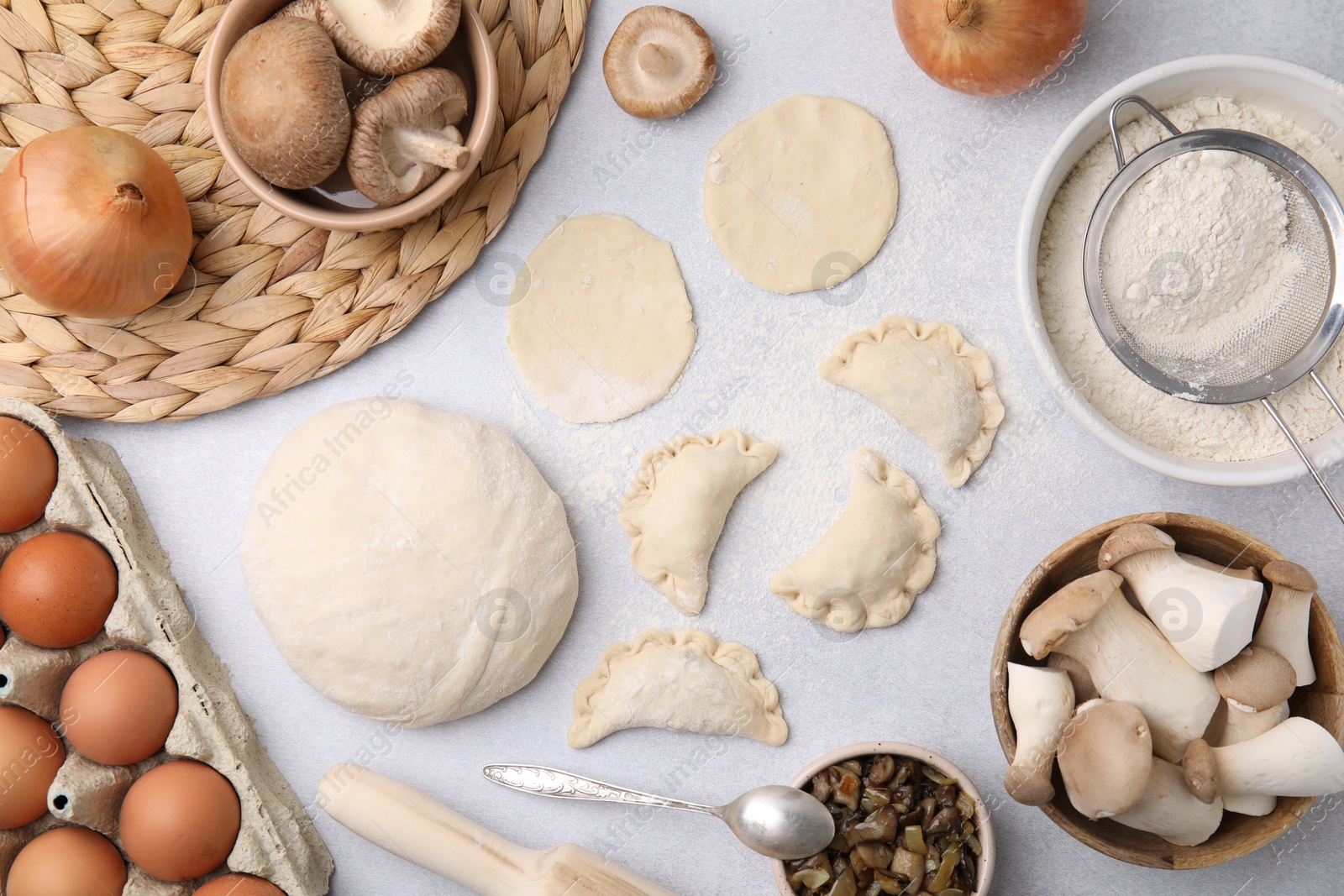 Photo of Process of making dumplings (varenyky) with mushrooms. Raw dough and ingredients on white table, flat lay