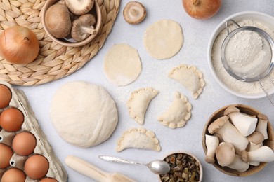 Process of making dumplings (varenyky) with mushrooms. Raw dough and ingredients on white table, flat lay