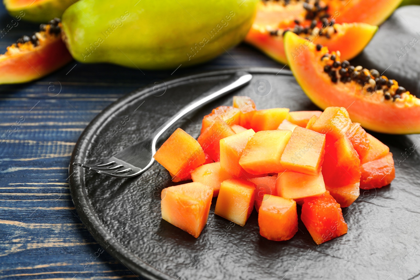 Photo of Diced fresh ripe papaya with fork on wooden table