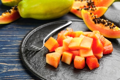 Diced fresh ripe papaya with fork on wooden table