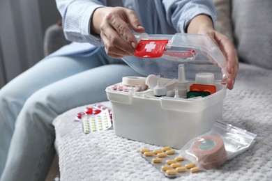 Photo of Woman opening first aid kit indoors, closeup