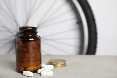 Photo of Pills on light grey table near bike wheel, space for text. Using doping in cycling sport concept