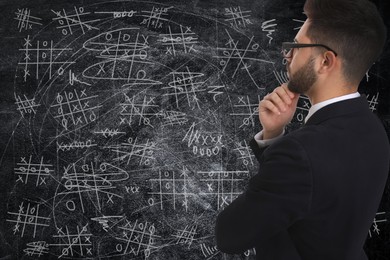 Image of Young businessman in elegant suit near blackboard with drawn tic tac toe game 