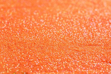Photo of Shiny orange glitter as background, closeup view
