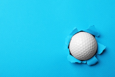 Photo of New golf ball stuck in color paper. Space for text
