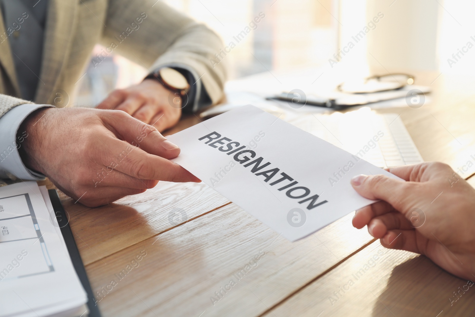 Photo of Employee giving resignation letter to boss in office, closeup