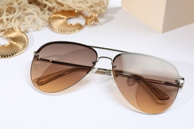 Photo of New stylish elegant sunglasses and jewelry on white background, closeup