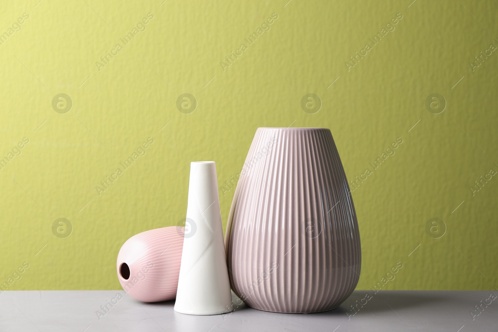 Photo of Stylish ceramic vases on grey stone table against green background