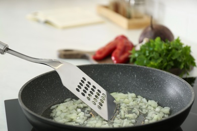 Photo of Frying chopped onion on stove in kitchen, closeup