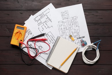 Wiring diagrams, office stationery, wires and digital multimeter on wooden table, top view
