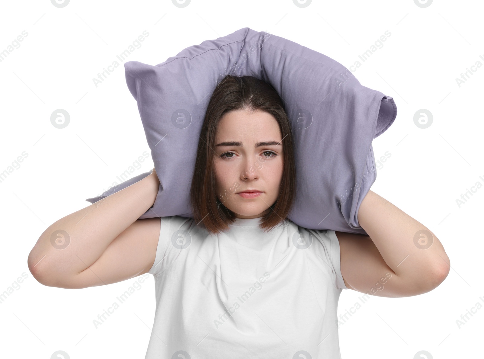 Photo of Unhappy young woman covering ears with pillow on white background. Insomnia problem