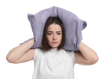 Photo of Unhappy young woman covering ears with pillow on white background. Insomnia problem