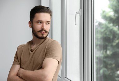 Photo of Handsome man near window indoors. Space for text