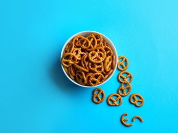 Photo of Delicious pretzel crackers in bowl on light blue background, flat lay