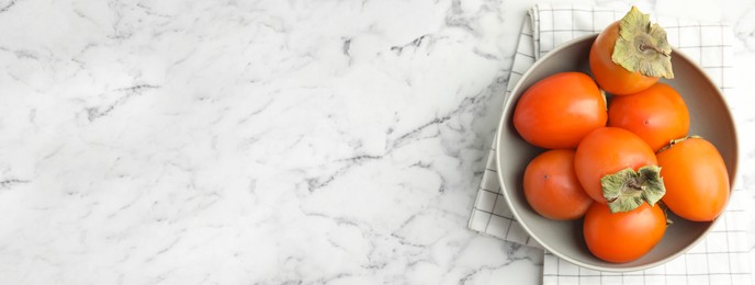 Image of Tasty ripe persimmons on white marble table, top view with space for text. Banner design