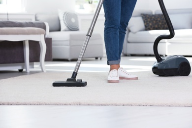 Photo of Woman cleaning carpet with vacuum cleaner, closeup