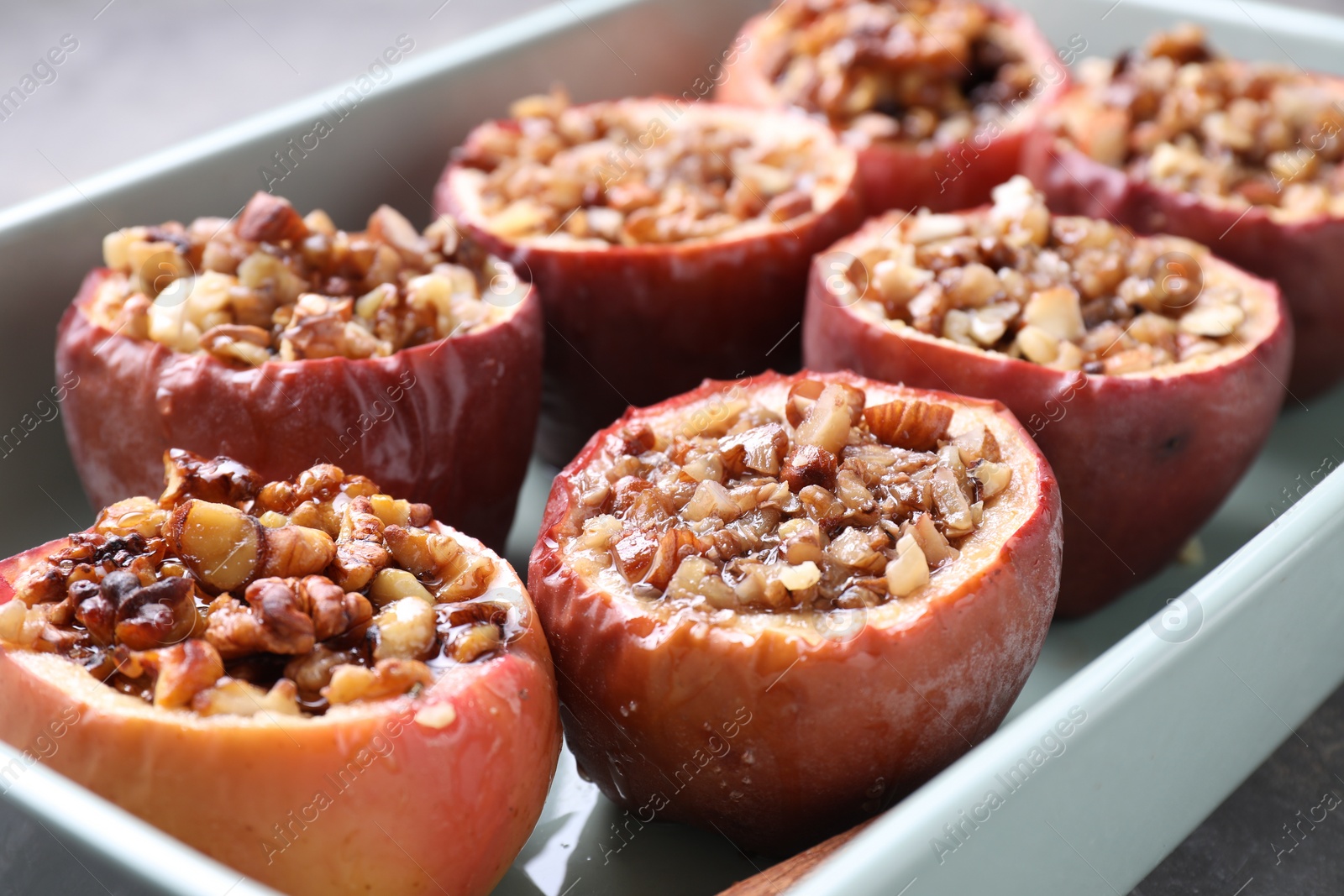 Photo of Tasty baked apples with nuts and honey in dish on table, closeup