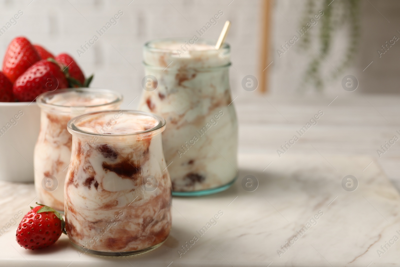 Photo of Tasty yoghurt with jam and strawberries on white marble table, closeup. Space for text