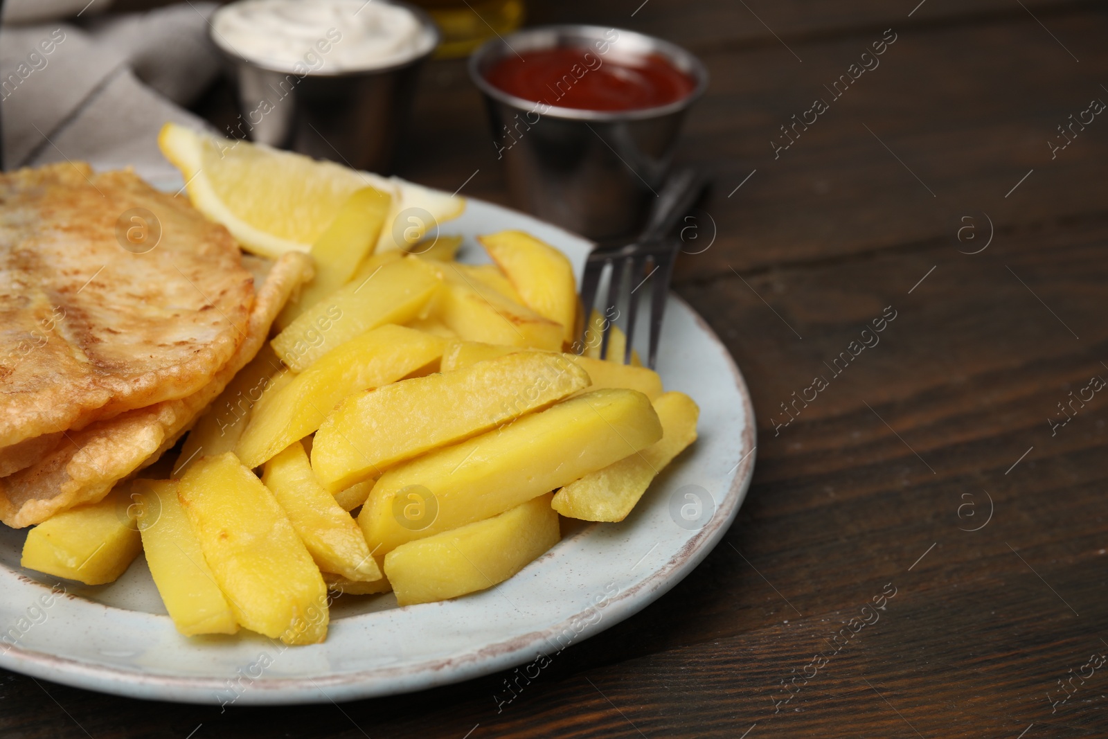Photo of Delicious fish and chips served on wooden table, closeup