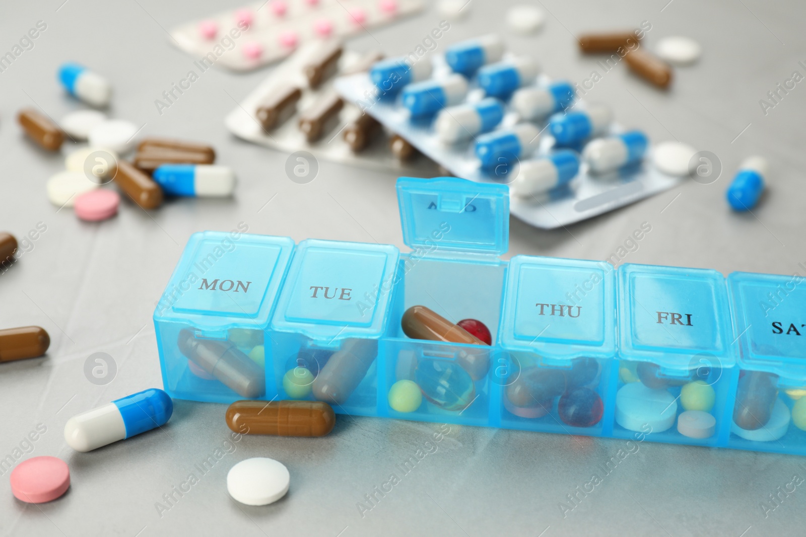 Photo of Plastic box with different pills on light grey stone table