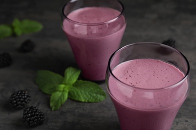 Photo of Glasses with blackberry yogurt smoothies on grey table, closeup