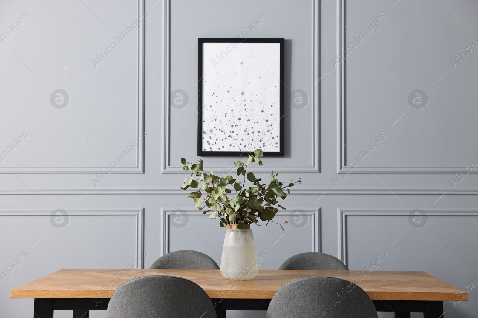 Photo of Vase with eucalyptus branches on wooden table in stylish dining room