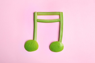 Photo of Musical note made of fruits and vegetables on color background, top view