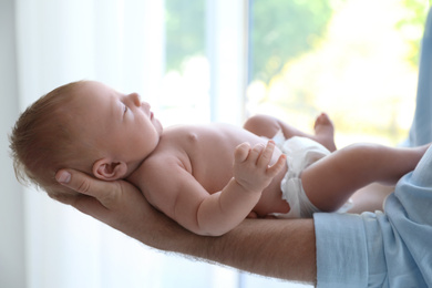 Photo of Father holding his newborn baby at home, closeup