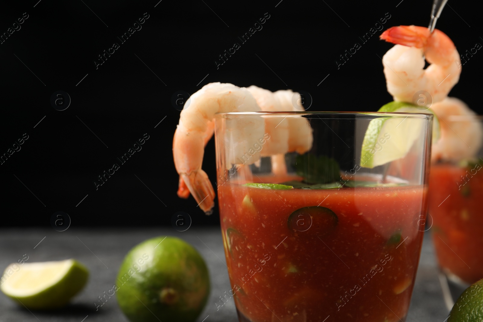 Photo of Tasty shrimp cocktail with sauce in glasses on grey table, space for text