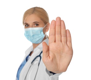 Doctor in protective mask showing stop gesture on white background. Prevent spreading of coronavirus