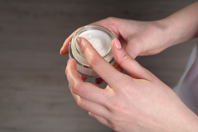 Woman applying hand cream indoors, above view