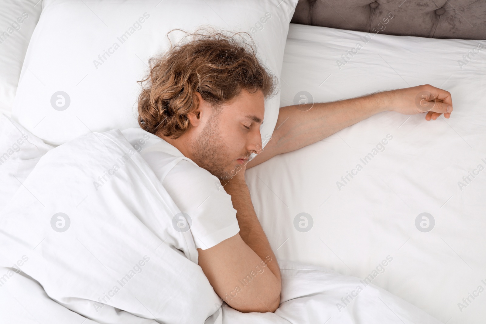 Photo of Handsome young man sleeping on pillow, view from above. Bedtime