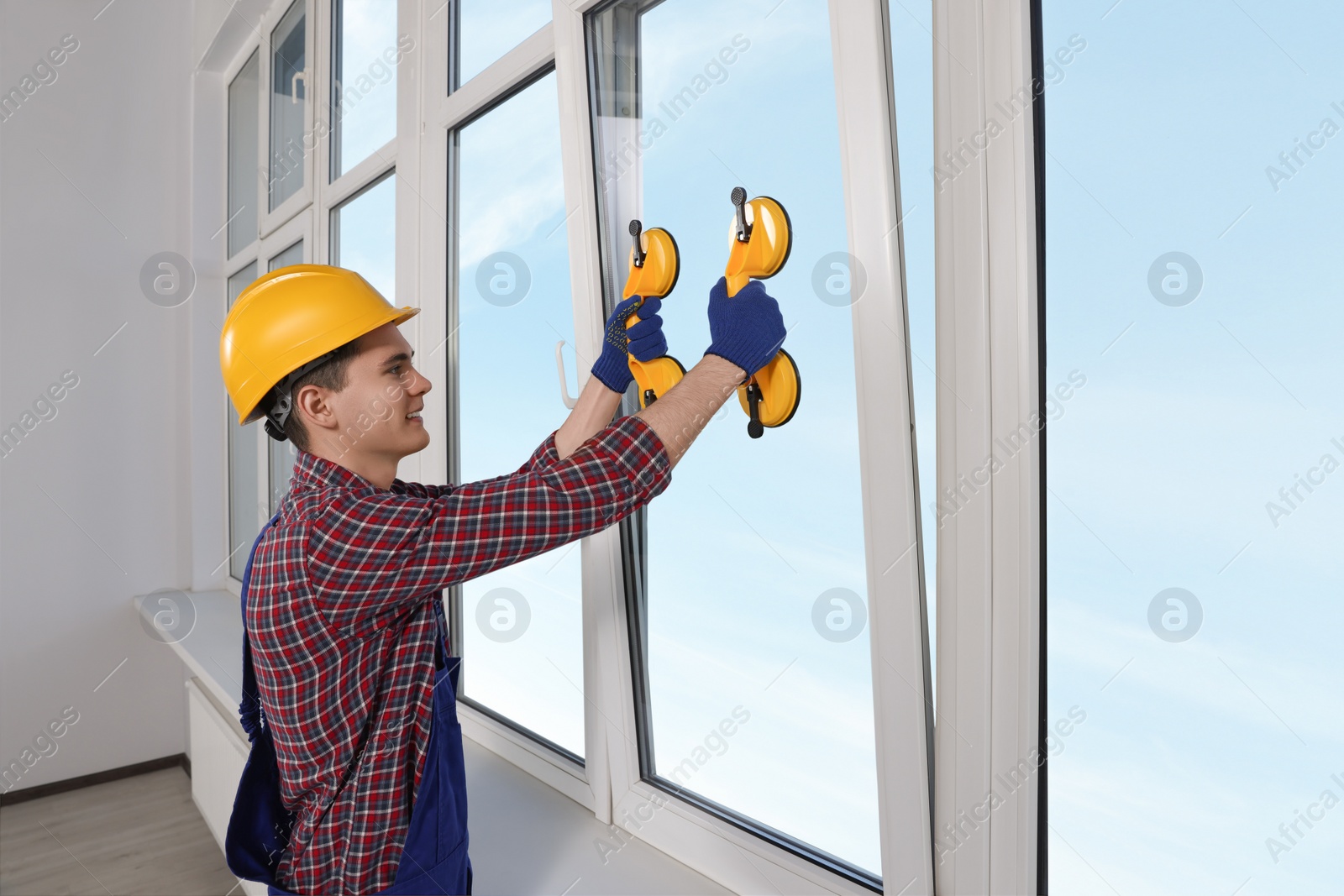 Photo of Worker using suction lifters during plastic window installation indoors